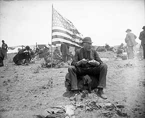 Photo: Participants in Coxey's Army have a meal in camp as they pass through Colorado. An American flag is staked in the ground, laundry hangs on a clothesline. Credit: Colorado Historical Society
