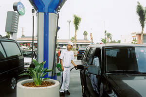 Gas station attendant fueling car at Regional Transportation Center, San Diego